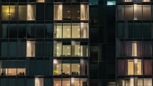 유리와 조명으로 다중층 건물의 창문에서 깜빡이는 시간당 시야를 가까이 사람들 — 비디오