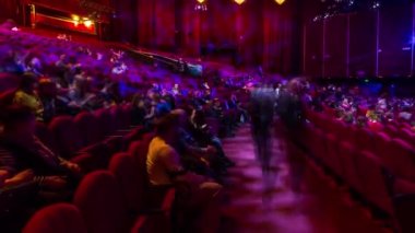 Seyirciler konser salonunda toplanıp gösteriyi zaman aşımına uğratarak izliyorlar. Kırmızı koltuklu büyük bir salon. Işığı kapatana kadar izleyiciler yerlerini dolduruyor. Sol taraftan panoramik görünüm