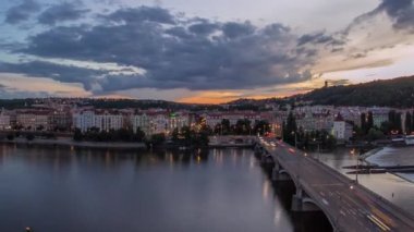 Ltava Nehri 'nin panoramik manzarası ve Prag Tepesi Petrin' in hava zaman çizelgesi ve Çek Cumhuriyeti 'nin güzel renkli gökyüzü ile Jirasek Köprüsü' nün gece gündüz geçişi. Dans salonunun tepesinden bak.