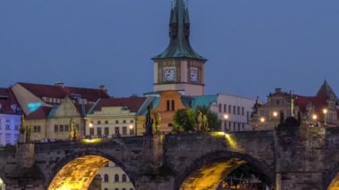 Charles Köprüsü gün gece geçiş timelapse Vltava Nehri için su Prag, Çek Cumhuriyeti için yansıtılır. İlluminater binalar ve eski şehir Kulesi