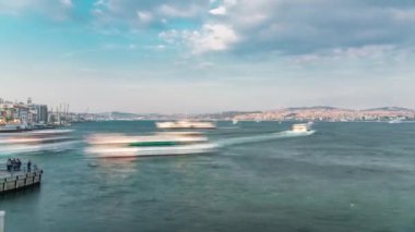 Panoramic view to tourist ship and ferris traffic on Bosphorus timelapse from Galata Bridge in Istanbul, Turkey. City skyline with Camlica hill on background before sunset at spring day