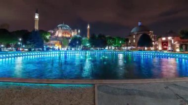 Hagia Sophia and Hamam in Istanbul old town night timelapse with blue illuminated fountain, Sultanahmet district, Turkey. Reflection on the water