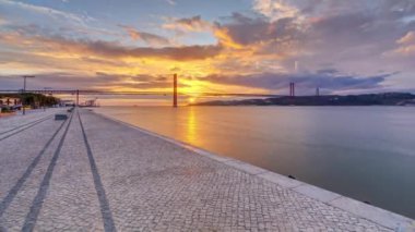 Lisbon city sunrise with April 25 bridge panoramic timelapse, River and waterfront early morning. Colorful cloudy sky