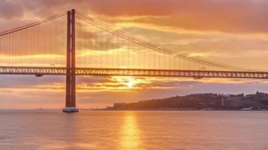 Lisbon city sunrise with April 25 bridge timelapse, River and waterfront early morning. Orange clouds on the sky
