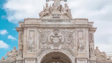 Top of Triumphal arch at Rua Augusta at Commerce square close up view timelapse in Lisbon, Portugal. Cloudy sky behind statues