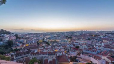 Lisbon after sunset aerial panoramic view of city centre with roofs at autumn day to night transition timelapse, Portugal. Top view from Sophia de Mello Breyner Andresen viewpoint. Lights turning on