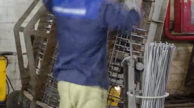 Üretim tesisi zaman ayarında yarı otomatik kaynaklamada elektrot ile çalışan kaynakçı. Üniformalı ve metal takviyeli işçiler.