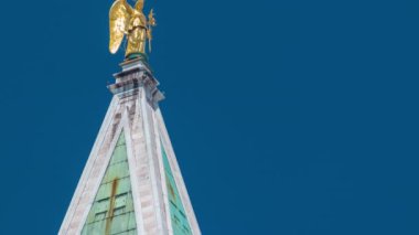 Top of tower on the famous 16th century cathedral on San Marco square timelapse. Its roof has an angel-topped spire belfry offering amazing views over Venice. Blue sky at summer day