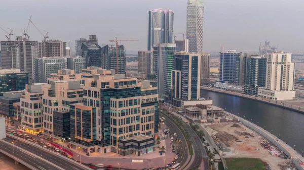 Bay Square district day to night transition timelapse. Mixed use and low rise complex office buildings located in Business Bay in Dubai. Aerial view from above with traffic on the road