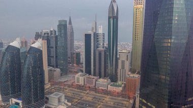 Dubai 'nin finans merkezi, gece gündüz aydınlık lüks gökdelenler geçiş zamanı, Dubai, Birleşik Arap Emirlikleri. Otoparkı ve çatısı olan hava manzarası