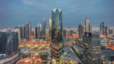 Panorama of futuristic skyscrapers in financial district business center in Dubai on Sheikh Zayed road night. Aerial view from above with illuminated towers with sunrise and long shadows