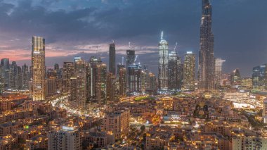 Dubai Şehir Merkezi 'nden gece geçişi, Dubai' deki Birleşik Arap Emirlikleri 'nde gün batımından sonra en yüksek gökdelen ve eski kasaba manzarası çevresindeki diğer kulelerle gerçekleşiyor. Işıklar yanıyor..