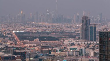Dubai Downtown with financial district skyline row of skyscrapers with tallest tower aerial night. Overview in a far distance from Dubai marina rooftop. Villa houses after sunset. UAE