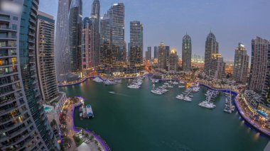 Dubai marina tallest skyscrapers panorama and yachts in harbor aerial night after sunset. View at apartment buildings, hotels and office blocks, modern residential development of UAE