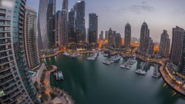 Dubai marina tallest skyscrapers and yachts in harbor aerial night panoramic before sunrise. View at apartment buildings, hotels and office blocks, modern residential development of UAE