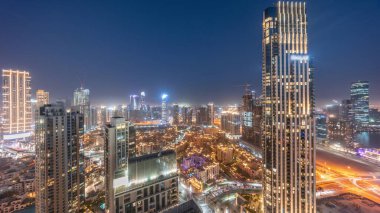 Büyük bir şehrin hava panoramik görüntüsü. Günbekten geceye geçiş zamanı. Dubai, Birleşik Arap Emirlikleri 'nin gökdelenleri ve geleneksel evleri olan iş sahası ve şehir merkezi..