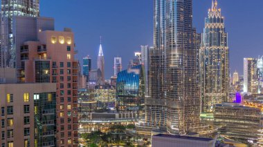 Dubai Uluslararası Finans Merkezi bölge gökdelenlerinin şehir merkezinden gece gündüz geçiş zamanının hava görüntüsü. Camdan ofis kuleleri ve modern binaları olan oteller.