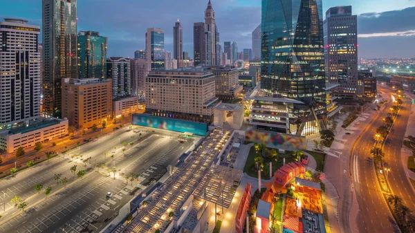 Dubai International Financial district night. Panoramic aerial view of business office towers and parking lot before sunrise. Illuminated skyscrapers with hotels and shopping mall