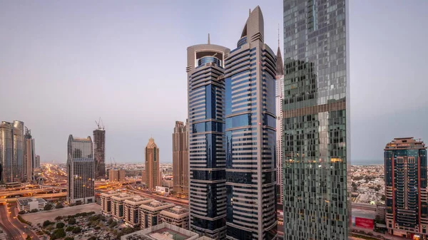 迪拜国际金融区的空中景观与许多摩天大楼夜以继日的过渡时间过去了 在有照明塔的停车场附近的路上 交通拥挤 阿联酋 — 图库照片