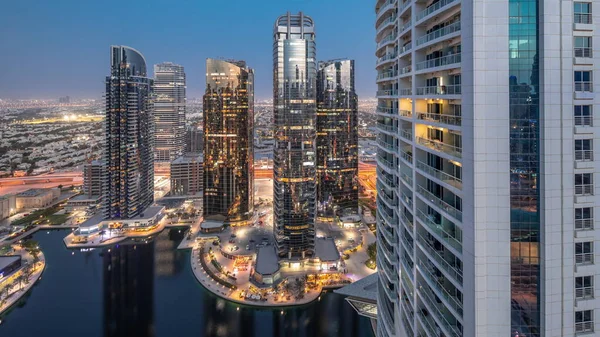 Tall residential buildings at JLT district aerial day to night transition timelapse, part of the Dubai multi commodities centre mixed-use district. Many balconies on towers