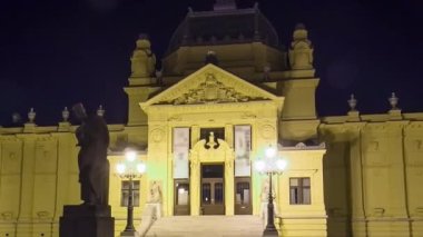 Art pavillion in Zagreb illuminated at night timelapse hyperlapse. Croatia. Monument in front of facade on lawn