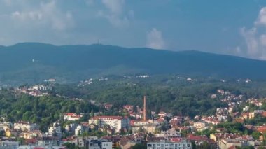 Aerial panorama of the city center timelapse of Zagreb, Croatia, with modern and historic buildings, mountains on background. Top view from skyscraper with cloudy blue sky
