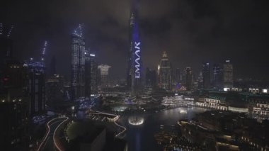 Dancing fountains at Dubai Mall near Burj Khalifa. Aerial view of beautiful fountain performance at night in popular tourist area in United Arabic Emirates