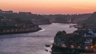Day to night transition aerial view of the historic city of Porto, Portugal panoramic timelapse from the Dom Luiz bridge. Illuminated waterfront and curved river from above
