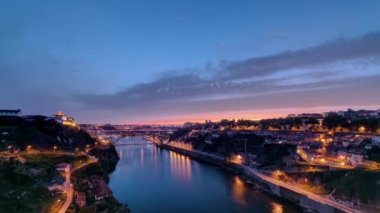 Günbegün Portekiz 'in tarihi Porto şehrinin havadan görüntüsü Dom Luiz köprüsü ile panoramik zaman dilimi. Aydınlatılmış kıyı şeridi yukarıdan nehre yansıyor