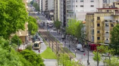 Traffic and metro line on the busy street near Jardim do Morro in Vila Nova de Gaia and Porto cityscape aerial timelapse with in Portugal, historic city centre from above