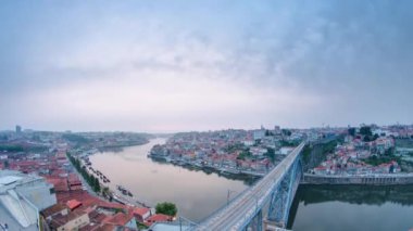 Day to night transition aerial view of the historic city of Porto, Portugal panoramic timelapse overview over the Dom Luiz bridge. Illuminated waterfront reflected in the river from above