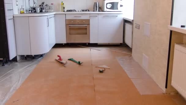 穿着绿色制服在厨房安装木地板的木匠工人在地板工作时间过去了 — 图库视频影像