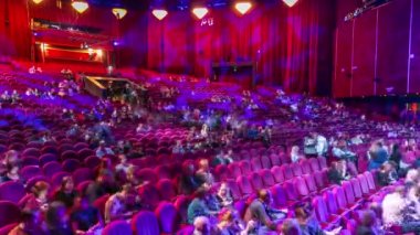 Seyirci toplantı salonunda toplamak ve tiyatro timelapse gösterisinde dikkat et. Kırmızı koltuk koltuk ile büyük salonu. Işığı kapat kadar yerleri doldurarak izleyiciler. Sol taraftan göster