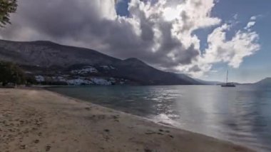 Panorama, mavi gökyüzünde bulutlarla Amorgos adasının havadan zamanlamasını gösteriyor. Geleneksel Yunanistan - tepeleri ve turkuaz denizi olan plaj, Kiklad