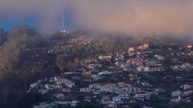 Funchal, Madeira, Portekiz 'deki tepedeki beyaz evlerin üzerinde gün batımı. Üstte turuncu bulutlar