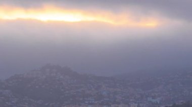 Tepedeki evlerin üzerinde bulutlarla gün batımı, Funchal, Madeira, Portekiz zaman çizelgesi