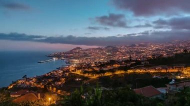 Gün batımından sonra adanın manzarası Funchal 'a gündüz, gece geçişi, Madeira, Portekiz zaman çizelgesi. Limanda akşam aydınlatması ve şehir ışıklarıyla