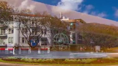 Madeira 'daki Funchal kasabası sokakları ve mavi bulutlu gökyüzü ile küresel zaman atlamalı çeşme. Dolambaçlı bir yolda, etrafta arabalar dolaşırken