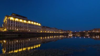 Ponte Alla Carraia 'nın alacakaranlık sahnesi ve gün batımından sonra sudaki yansımalarla Arno Nehri üzerinde gece gündüz tarihi binalar aydınlatmıştır. Floransa, Toskana, İtalya