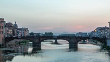 Santa Trinita Kutsal Üçlemeci Köprüsü 'nün alacakaranlık sahnesinde gün batımından sonra suya yansıyan yansımalarla Arno Nehri üzerindeki geçiş zamanı. Floransa, Toskana, İtalya