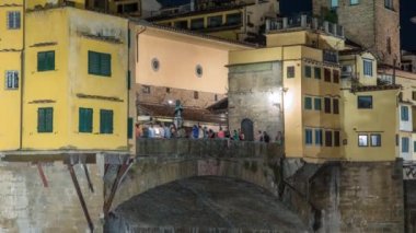 İtalya 'nın Floransa kentindeki Arno Nehri üzerindeki ünlü Ponte Vecchio köprüsü gece aydınlandı. Merkezde bir sürü insan var. Görüntüyü kapat.