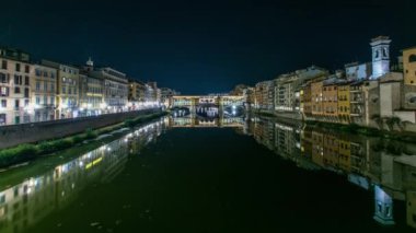 İtalya 'nın Floransa kentinde Arno nehri üzerindeki ünlü Ponte Vecchio köprüsü gece aydınlandı. Suyun yansıması. Yan taraftaki eski evler