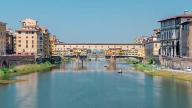 Ponte Vecchio güneşli bir günde panoramik zaman diliminde, İtalya 'nın Floransa kentindeki Arno Nehri üzerindeki ortaçağ taş segmental kemer köprüsünde, bir zamanlar olduğu gibi hala dükkanlar inşa edildiği biliniyor.