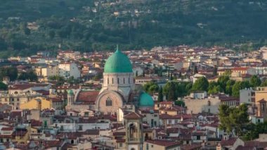 Floransa sinagogu, yeşil bakır kubbe ile çevreleyen banliyö evlerinin üzerinde yeşil yamaç arkasında yükseliyor. Michelangelo Meydanı 'ndan gün batımından önce gökyüzü manzarası