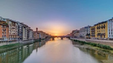 Arno Nehri üzerindeki şehir manzarası. Floransa 'da günbatımında Kutsal Üçlemeci Köprüsü' nün ünlü zamanlaması. Sudaki yansımalar. Yan taraftaki eski renkli evler
