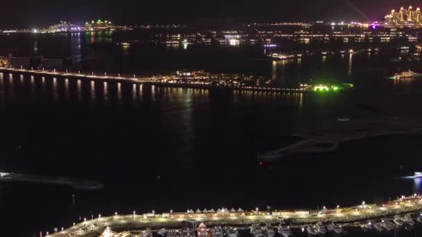 从迪拜滨海鸟瞰全景到棕榈树岛的空中风景 从上面俯瞰 有照明的酒店和别墅 港湾内的游艇和船只 — 图库视频影像