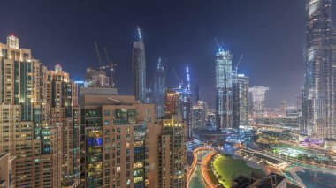 Dubai şehir merkezindeki gökdelenlerin ufuk çizgisi fıskiyelerin yanı ve akşam havası gecesinde park yeri. Aydınlatılmış kuleler ve inşaat alanı