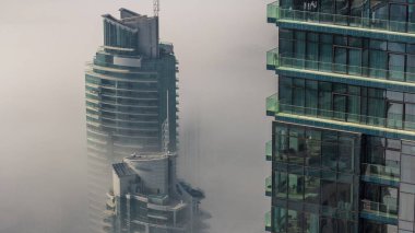 Dubai Marina ufuk çizgisi ve cam gökdelenler üzerinde nadir bulunan kış sisi ile kaplı kuleler. Üst görünüm bulutların üstünde. Dubai, BAE