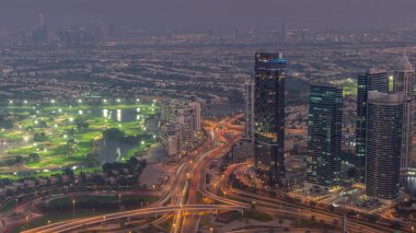 Big crossroad junction between JLT district and Dubai Marina intersected by Sheikh Zayed Road aerial day to night transition . Cars traffic near illuminated skyscrapers