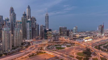 Panorama of Dubai Marina and media city highway intersection spaghetti junction day to night transition after sunset. Illuminated tallest skyscrapers on a background. Aerial top view from JLT district